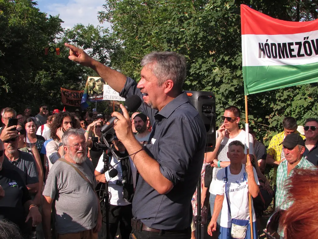 Der Abgeordnete Ákos Hadházy zeigt mit ausgestrecktem Arm in Richtung des umstrittenen Anwesens Hatvanpuszta.