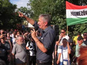 Der Abgeordnete Ákos Hadházy zeigt mit ausgestrecktem Arm in Richtung des umstrittenen Anwesens Hatvanpuszta.