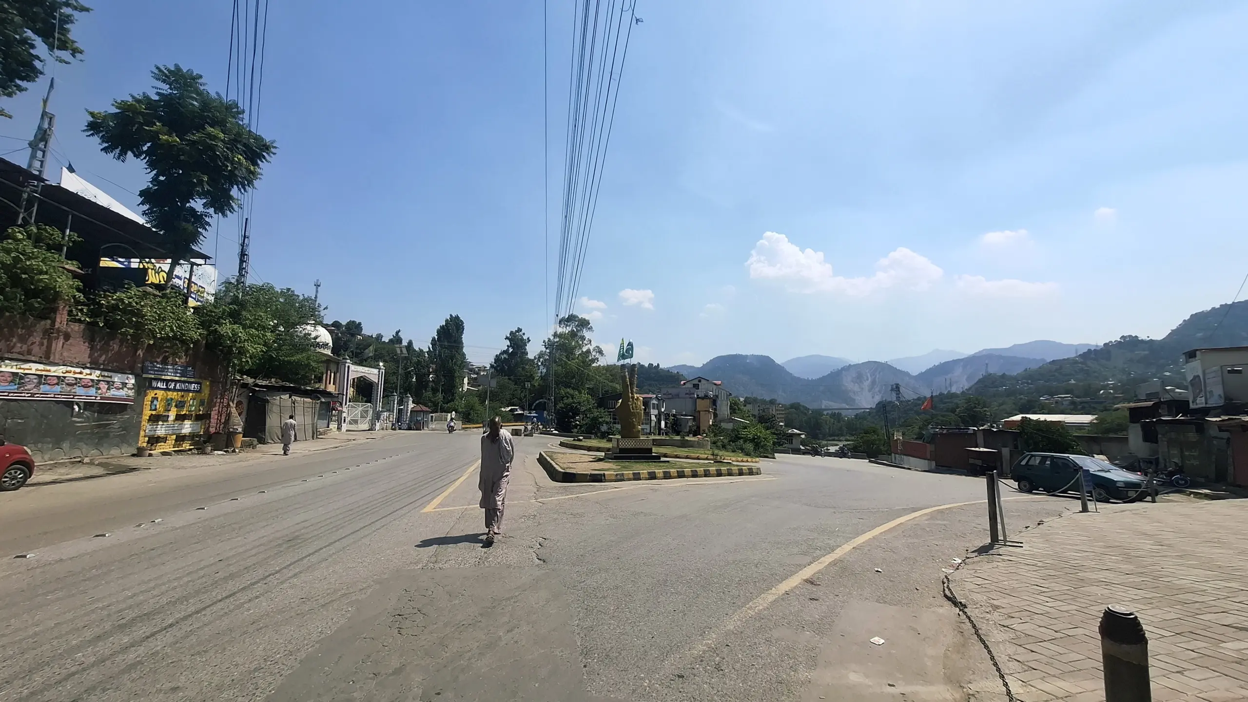 Photo: An elderly resident walks down an empty central roadway in Muzaffarabad during midday heat, amid a region-wide commercial shutdown and traffic suspension.