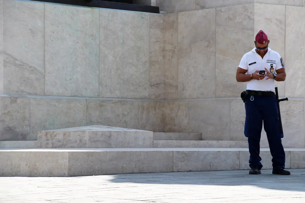 Mehrere ungarische Polizisten stehen in Uniform auf dem Kossuth-Lajos-Platz in Budapest, im Hintergrund sind Gebäude des Stadtteils Lipótváros zu sehen.