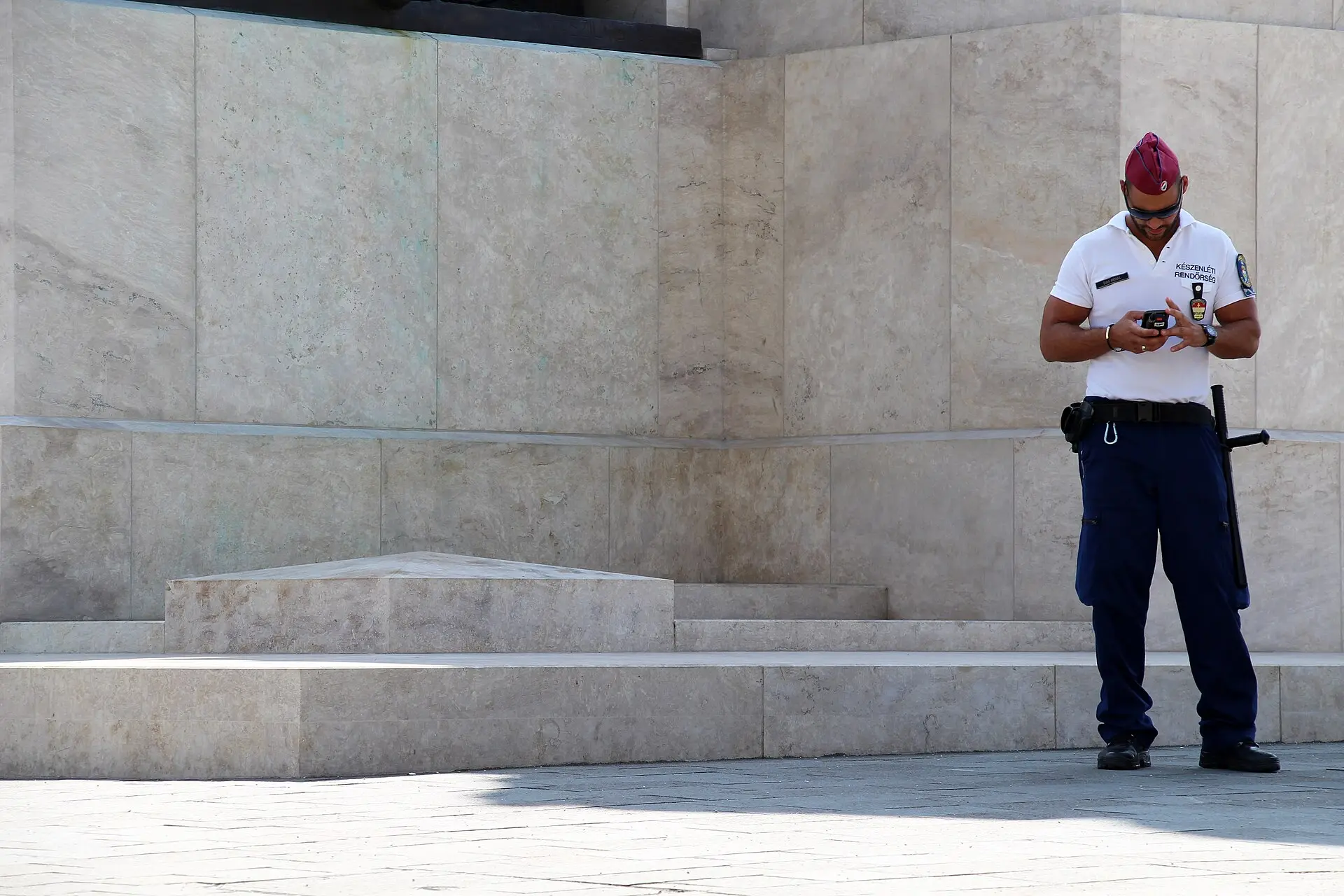 Mehrere ungarische Polizisten stehen in Uniform auf dem Kossuth-Lajos-Platz in Budapest, im Hintergrund sind Gebäude des Stadtteils Lipótváros zu sehen.