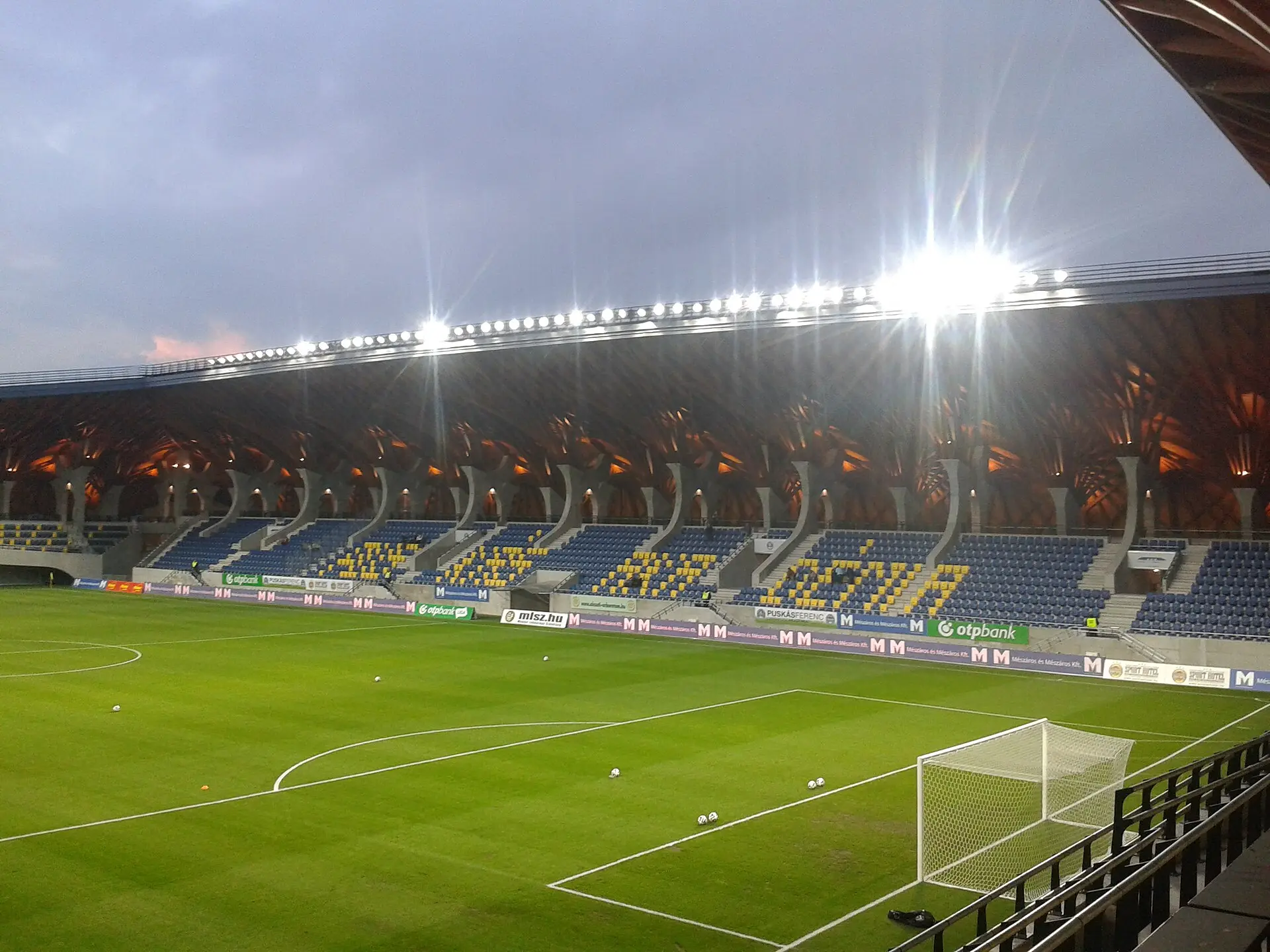 Blick in die leere Pancho Arena in Felcsút mit überdachten Tribünen und Fußballfeld.